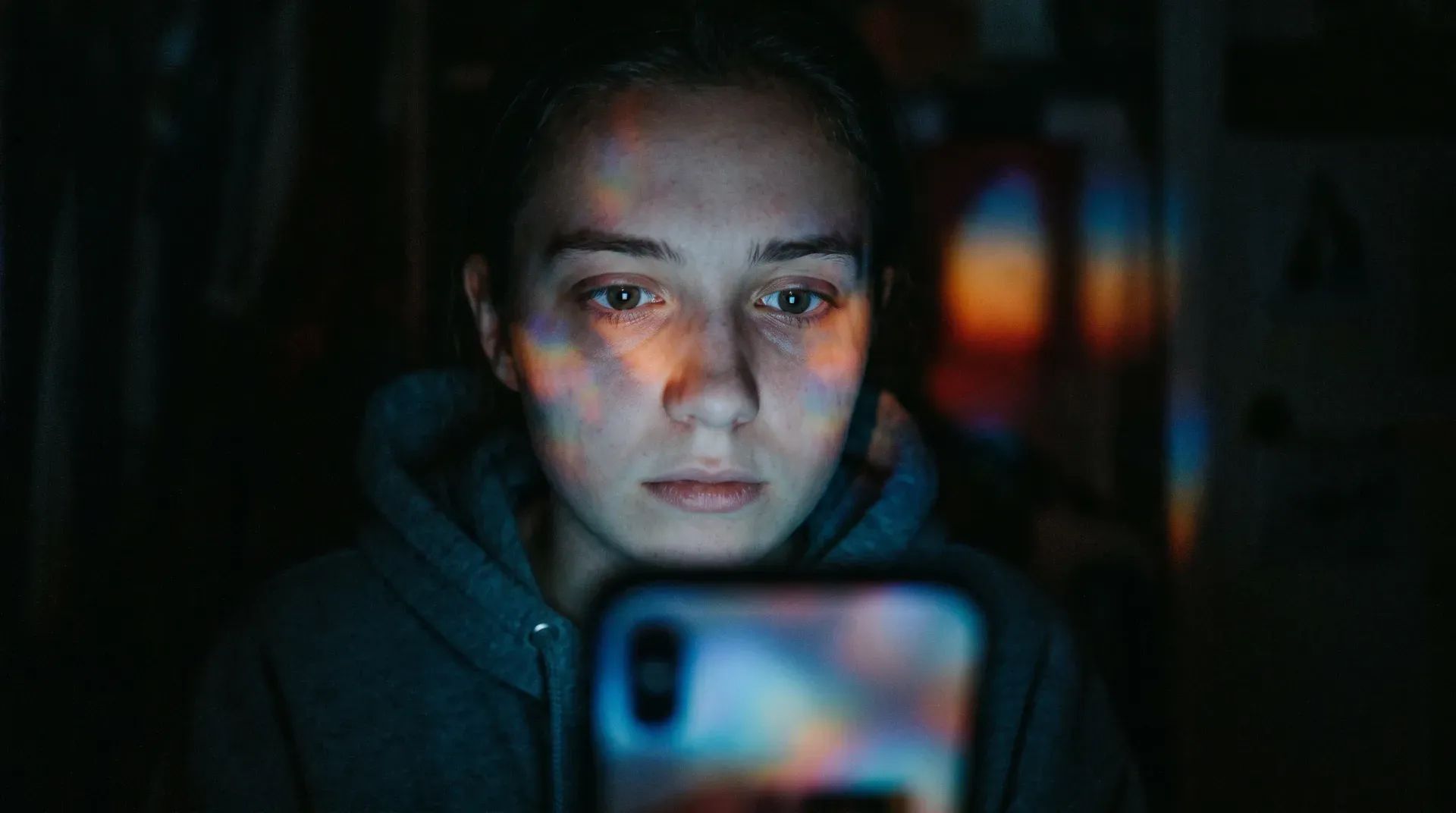 Ein junges Gesicht, allein vom grellen Schein eines Smartphones erleuchtet, bunte Reflexe in den Augen, zwischen Aufregung und Erschöpfung — drei Uhr nachts